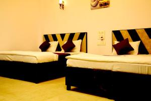 two beds sitting next to each other in a room at Hotel Bhatner Inn in Hanumāngarh +9 photos