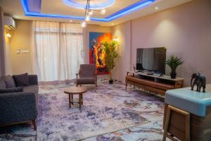 a living room with a television and a couch and a table at Appartements Quartier Kabulameshi - Lubumbashi in Lubumbashi