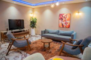 a living room with a couch and a tv at Appartements Quartier Kabulameshi - Lubumbashi in Lubumbashi +4 photos
