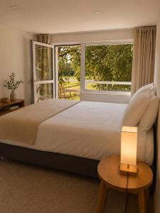 a bedroom with a large bed and a large window at Quinta Farm Stay - Silence and Nature Retreat in Lousã