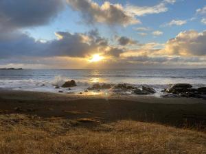 a sunset on a beach with the ocean at Between sea and big mountains in Leirá