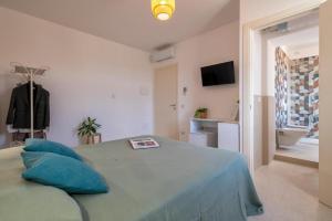 a bedroom with a bed with blue pillows and a bathroom at Opera Rooms Alghero in Alghero