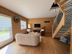 a living room with a couch and a staircase at Ferme du Bien Hêtre Gîte Cosy in Saint-Arnoult