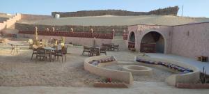 an outdoor patio with tables and chairs and a building at Agmair Amellal in Siwa