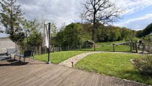 a wooden deck with an umbrella and a lawn at Ferme du Bien Hêtre Gîte Cosy in Saint-Arnoult