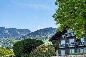 a house on a hill with mountains in the background at Waterfront in Lugrin