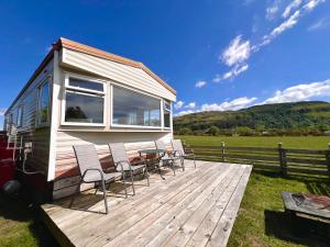 a tiny house with chairs and a table on a deck at Hawthorn Self Catering Cottages in Benderloch