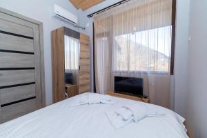 a bedroom with a white bed and a television at Hotel Chateau Ochia in Koromkhet'i