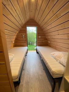 two beds in a wooden room with a window at Domaine de l'Ours / Camping Lodge in Saint-Urcize