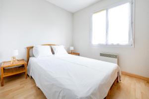 a white bedroom with a large bed and a window at Plein soleil, Capbreton in Capbreton