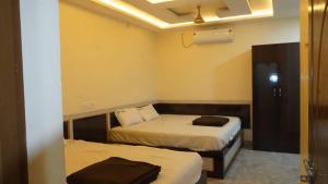 a room with two beds and a door to a bedroom at Hotel vasaavi Rameswaram in Rāmeswaram