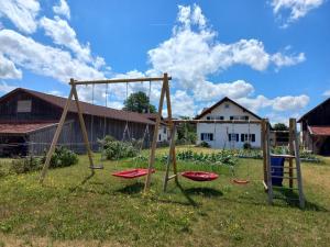 a swing set in a field with a house at Ferienwohnung Thomas in Landsberg am Lech