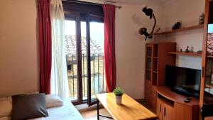 a living room with a tv and a large window at Casa Senderuela by CARDI Suites in Valdelinares