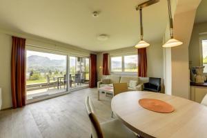a living room with a table and chairs and a large window at Seepark Drobollach in Drobollach am Faaker See
