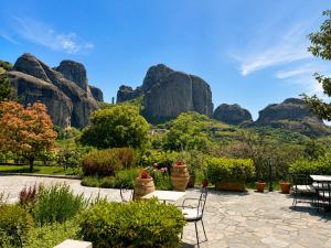 a patio with tables and chairs in front of rock formations at Hotel Doupiani House in Kalabaka