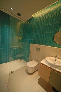 a green tiled bathroom with a toilet and a sink at Better Suites Hotel in Meppādi