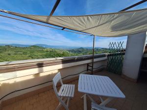 a balcony with two chairs and a table and an umbrella at Casa Panorama Assisi in Perugia