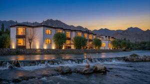a resort with a river and mountains in the background at The Nature Residency - A Riverside Resort in Leh in Leh