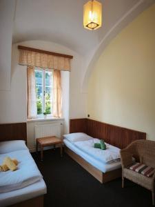 a room with two beds and a chair and a window at Zámeček Bischofstein in Teplice nad Metují