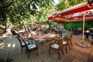 un patio con mesa, sillas y sombrilla en Hotel La Gil en Bucarest