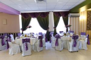 ブカレストにあるHotel La Gilの紫の弓付き白いテーブルが備わる宴会場