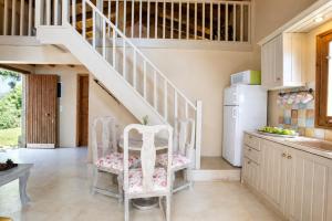 a kitchen with a staircase and two chairs at Anerada Houses - Seaviews Above Egremni in Lefkada in Athani +10 photos