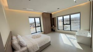a bedroom with a white bed and a large window at Horizon Stay Nizwa in Firq