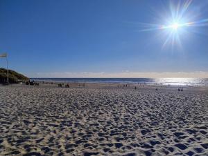 a sandy beach with the sun in the sky at Henne Station, Midtiby B & B in Henne