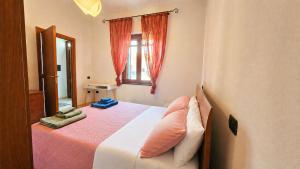 a bedroom with a bed with orange curtains and a window at Casa Are in Oristano