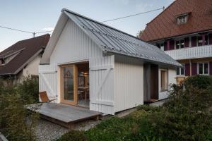 a white house with a porch and a wooden deck at Tiny House Amélie in Bonndorf im Schwarzwald