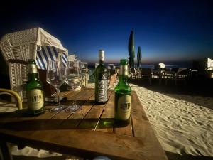 three bottles of wine and glasses on a table on the beach at Villa Topas in Wilhelmshaven