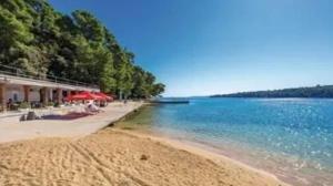 a beach with chairs and umbrellas next to the water at Rab Studio first floor 32m2 in Kampor