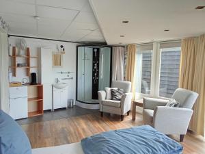 a room with a bed and two chairs and a sink at B&B aan het water in Earnewâld