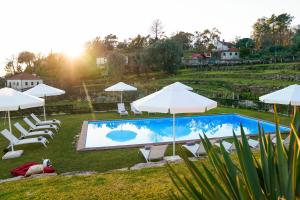 a pool with white umbrellas and lounge chairs at Casas de Selim in Arcos de Valdevez