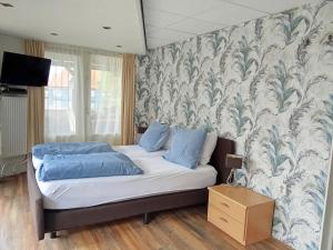 a bedroom with a bed with blue pillows and a wall at B&B aan het water in Earnewâld