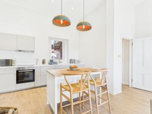 a white kitchen with a wooden table and chairs at Laura's House in Coupar Angus +1 photo