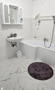 a white bathroom with a sink and a bath tub and a sink at Balatoni HUNOR Vendégház in Balatonvilágos +36 photos