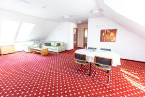 a room with a table and chairs on a red carpet at Hotel Bau Maribor in Maribor