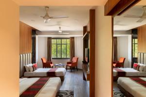 a hotel room with two beds and a table at Hotel Rock Regency Mount Abu - A Boutique Rodetel in Mount Ābu