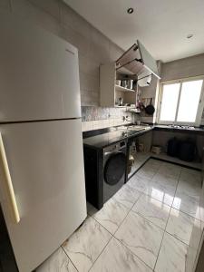 a kitchen with a white refrigerator and a dishwasher at Apparemment TAMARIS in Dar Bouazza
