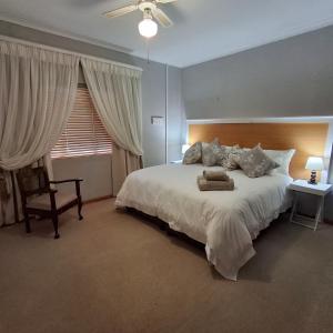 a bedroom with a large white bed and a chair at Vir Oulaas Guesthouse in Nieuwoudtville