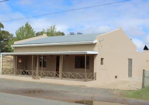 a small white house on the side of a street at Vir Oulaas Guesthouse in Nieuwoudtville