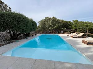 a large blue swimming pool with chairs and trees at Résidence Alba in Bonifacio