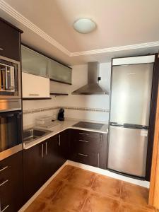 a kitchen with brown cabinets and a stainless steel refrigerator at Golden Vedra Residences in Pontevedra