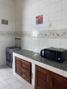 a kitchen with a counter with a microwave and a stove at Meublé de toursime L'Escale in Yaoundé