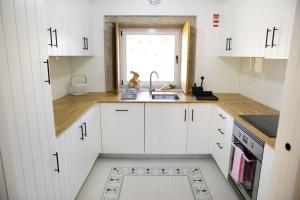 a kitchen with white cabinets and a sink and a window at Casas de Selim in Arcos de Valdevez +9 photos