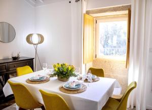 a white table with yellow chairs and a window at Casas de Selim in Arcos de Valdevez