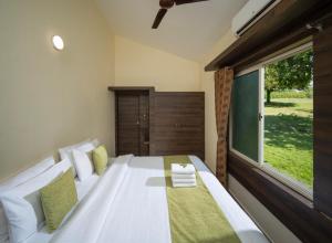 a bedroom with a white bed with a large window at The Wild Forest Resorts in Masinagudi +25 photos