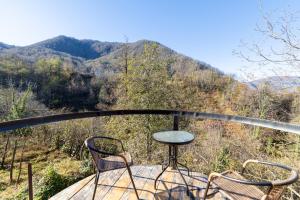 a table and two chairs on a balcony with a mountain at Cottages Chateau Ochia in Koromkhet'i