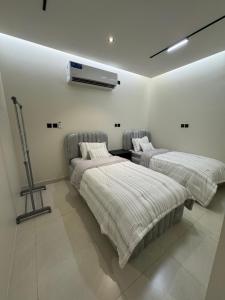 two beds in a room with a tv on the wall at شاليه لوسيندا in Baljurashi +10 photos